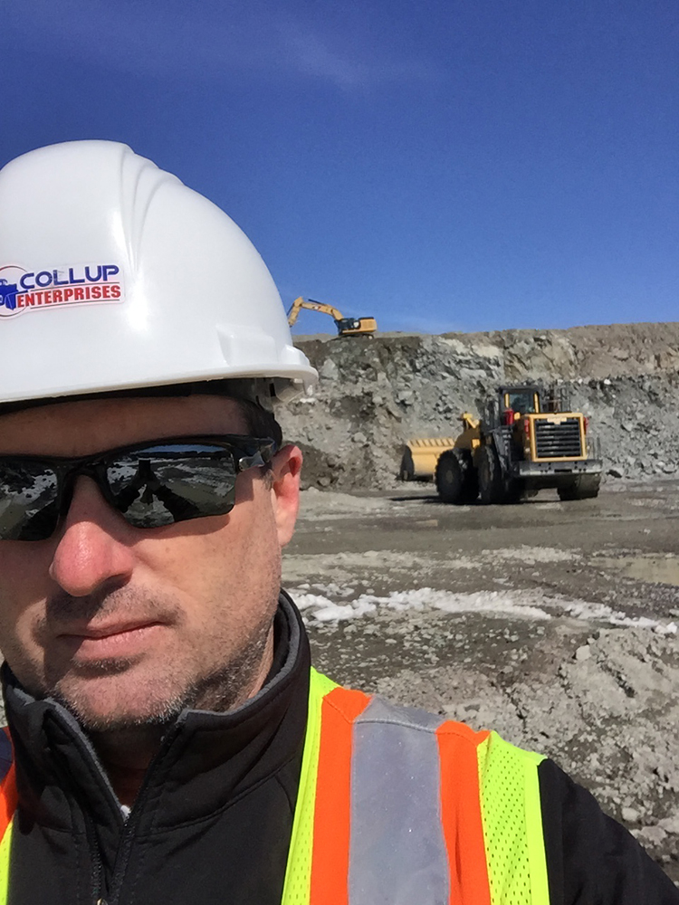 A Collup Enterprises team member standing near a wheel loader at a quarry operation