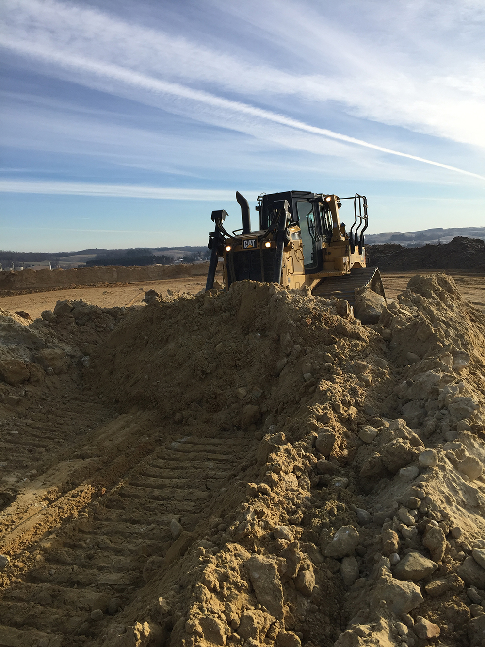 Track dozer pushing a dense bank of soil across an earthmoving site