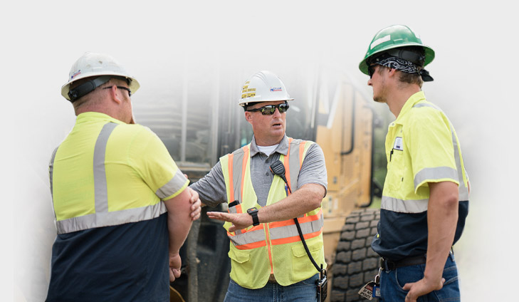 A Collup Enterprises instructor discussing equipment operation with two crew members wearing hard hats