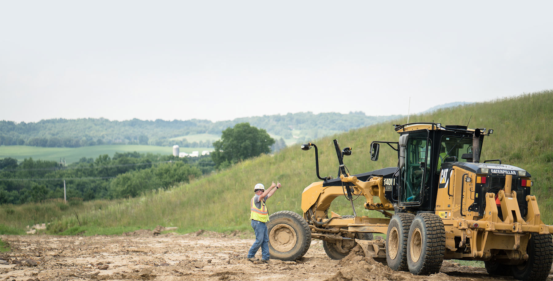 A Collup Enterprises instructor directing a motor grader operator during field training