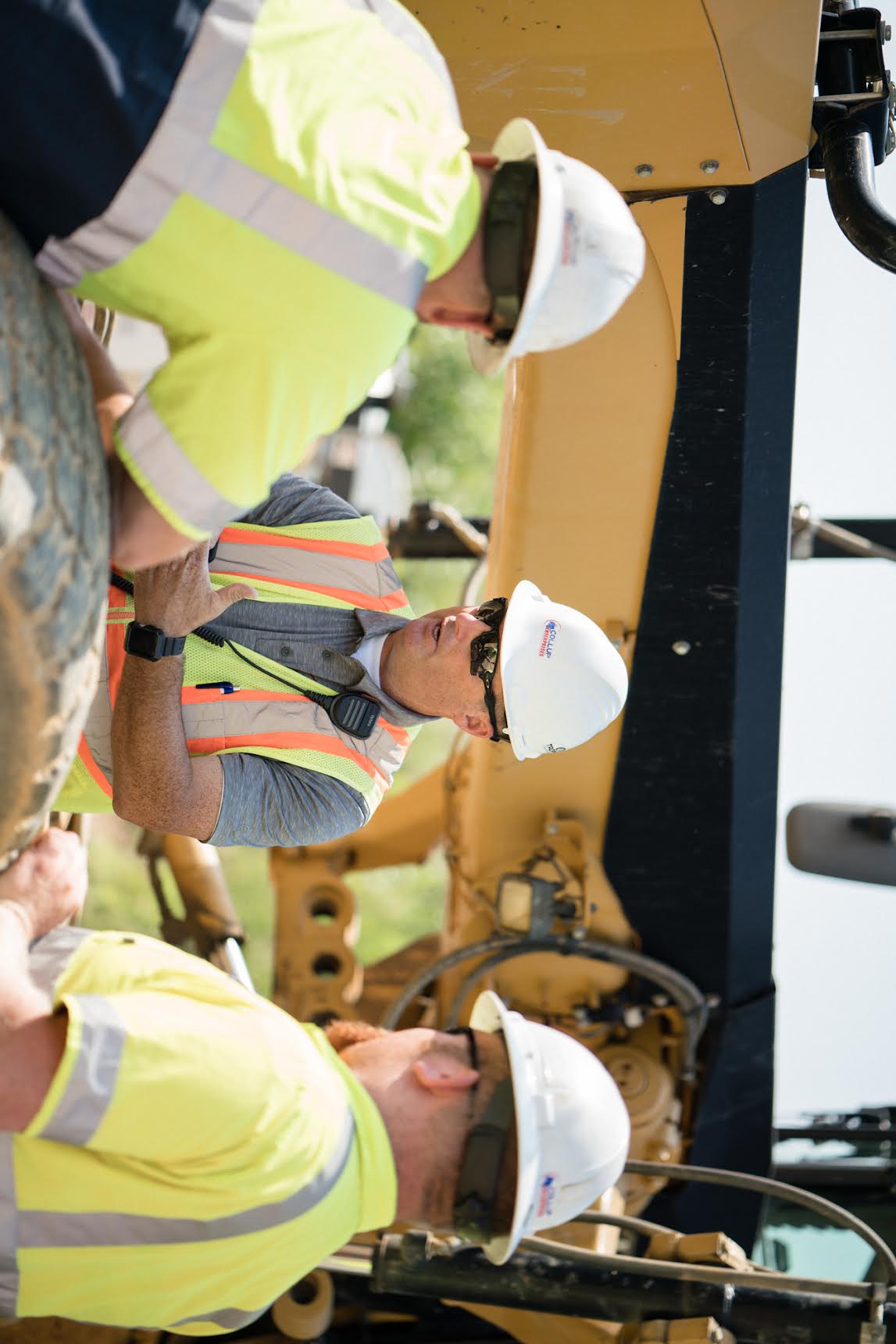 A field instructor speaking with an equipment operator beside a machine
